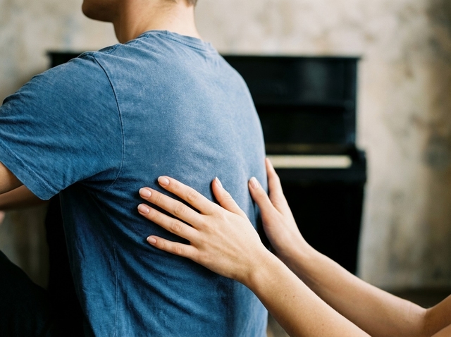 Une main accompagne le dos d'une chanteuse pour guider l'ancrage de la respiration.